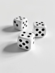 Three white dice are sitting on a white surface. The dice are all the same size and shape, and they are all facing the same direction. Concept of order and uniformity, as the dice are all identical