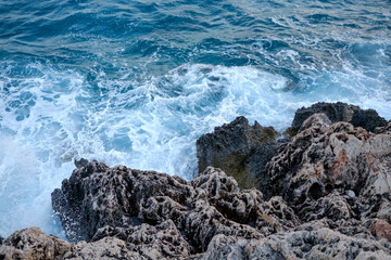 Beautiful view of water crashing on the rocky shore. Wave splashing against stones on shore close up.