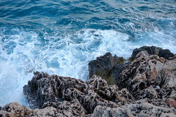 Beautiful view of water crashing on the rocky shore. Wave splashing against stones on shore close...