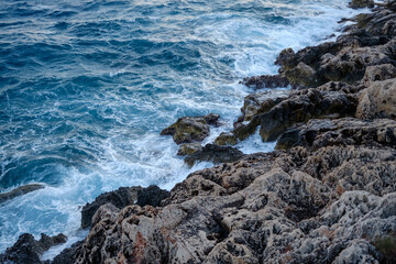 Beautiful view of water crashing on the rocky shore. Wave splashing against stones on shore close up.