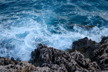 Beautiful view of water crashing on the rocky shore. Wave splashing against stones on shore close up.