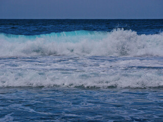 Turquoise blue sea water with white foam on waves. Stylized background abstract texture photo. Tenerife, Puerto de la Cruz
