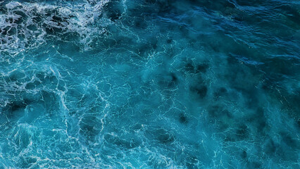 Aerial photo of a sea water surface. Turquoise blue water with white foam on waves - view from above. Stylized background abstract texture photo. Tenerife, Puerto de la Cruz