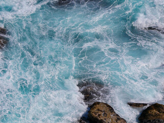 Aerial photo of a sea water surface. Turquoise water with foam on waves - view from above. Water...