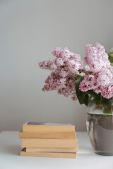Stack of old books with lilacs in vase, cottagecore aesthetic background