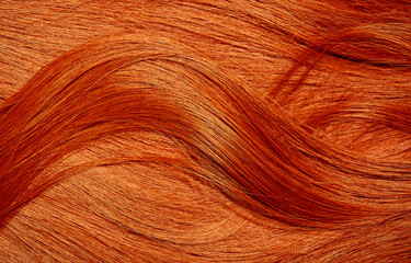 Red hair close-up as a background. Women's long orange hair. Beautifully styled wavy shiny curls....