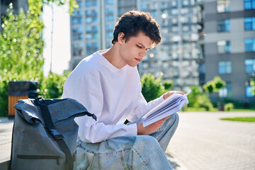 Handsome young male university college student reading a book