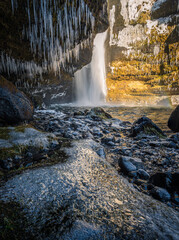 cascata islandese vista da una caverna, con stalattiti di ghiaccio