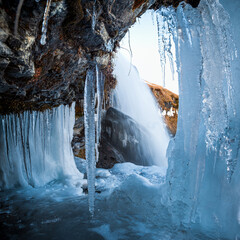 cascata islandese vista da una caverna, con stalattiti di ghiaccio