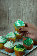 patties with green cream held by female hands on wooden background