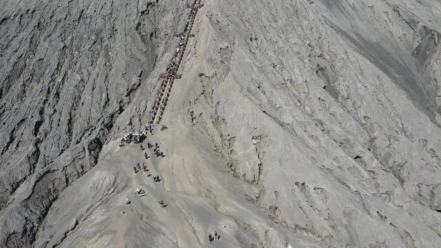 The caldera and the peak of Mount Bromo from a height. It looks like the tourists are climbing and enjoying the peak. Mt.Bromo is a popular tourist destination in East Java, Indonesia