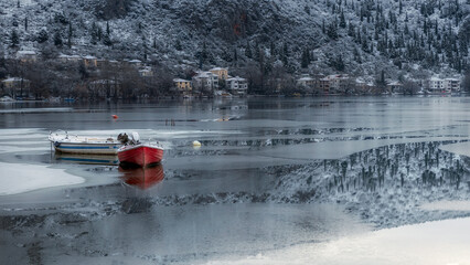 frozen parts of lake with red  boat