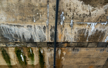 Fleckige und mit Moos bewachsene Wand einer Flussbrücke