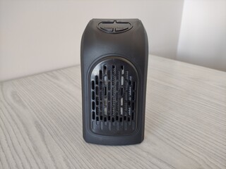 Black electric mini air heater for room on the wooden table