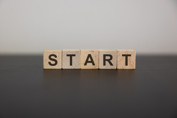 A row of wooden cubes with start text on the table. New beginning of life, business or career...