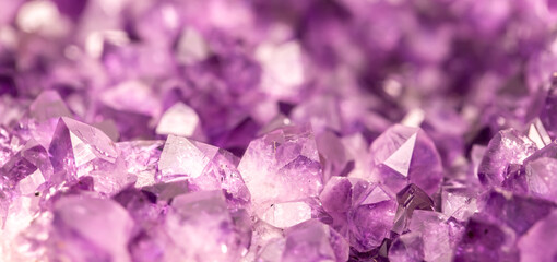 Amethyst purple crystals. Gems. Mineral crystals in the natural environment. Texture of precious and semiprecious stones. Seamless background with copy space colored shiny surface of precious stones.