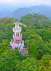 White concrete observation tower middle of a natural forest Ariel view with green exotic trees 