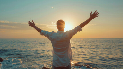 Silhouette of a person with arms outstretched facing the ocean during a beautiful sunset