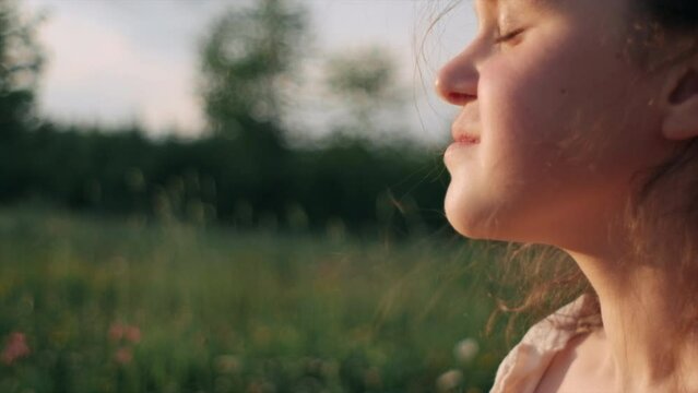 Close up portrait of charming happy little girl laughing and. Pretty positive preteen kid poses funny and smiling enjoying outdoors during warm summer sunset. Childhood and leisure time