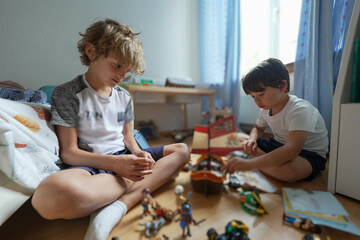 Two young boys playing with toys on the floor, enjoying a playful and imaginative moment together...