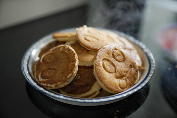 A plate of smiley face pancakes, fresh and ready to be served. These fun and cheerful pancakes make a delightful and tasty breakfast, perfect for starting the day with a smile.