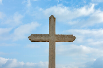 Stone Cross Against Blue Sky with Clouds - Religious Stock Photo