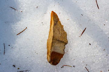 Stone tip lying on white snow, Stone Age flint tool, Russia