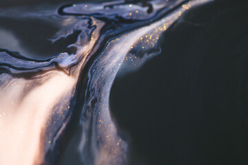 Colorful liquid paint abstract background. Blue, white and black acrylic paints with shining golden...