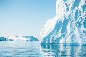 Big icebergs in Atlantic ocean, Ilulissat icefjord, western Greenland. Blue sea and the blue sky