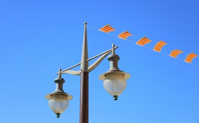 Street lamp with Catalan flag ribbons attached against backdrop of blue sky