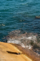 Sea waves on the rocky beach. Ocean shore on a sunny day. 