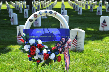 A remembrance wreath in from of rows of grave stones in a National cemetery decorated with American...