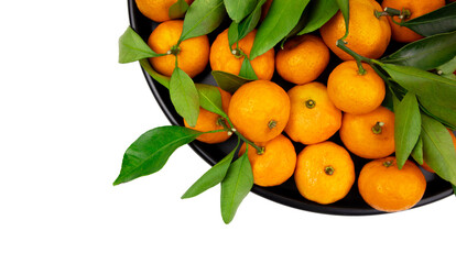 tangerines with green leaves on a black plate top view isolated on white