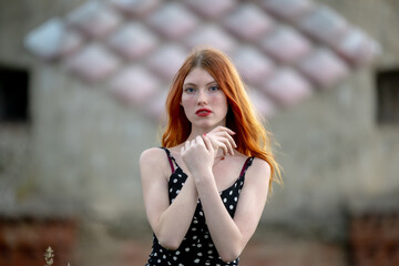 Naklejka premium Portrait of a redhead girl with long hair at the city.
