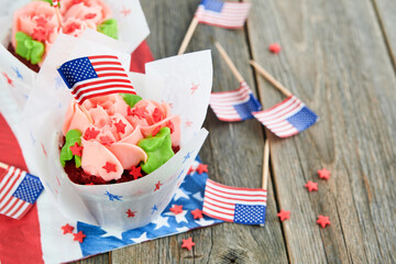 Patriotic cupcake 4th july with american flag. Delicious cupcake with cream cheese and blue and red toping on old wooden background. Dessert food for American Independence Day celebration.