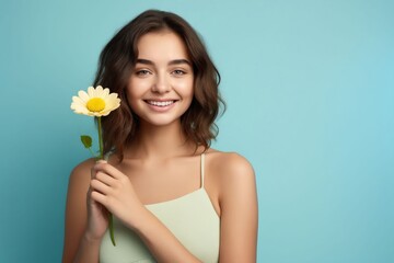 Beautiful woman holding a flower on blue background.