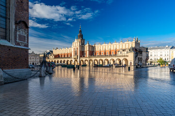 Renaissance Cloth Hall on Krakow Main Square reflecting in the wet cobblestones, sunny morning,...