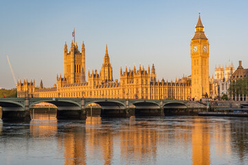 Early sunny morning with Palace of Westminster and Big Ben clock tower seen across River Thames,...