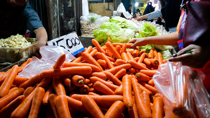 shop owner of the store receiving basket of vegetable. hand of asian woman pick carrot in traditional market