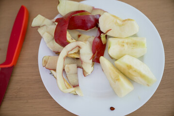 Rustic plate of freshly sliced apples and peels on a wooden table, highlighting simple and healthy snacking