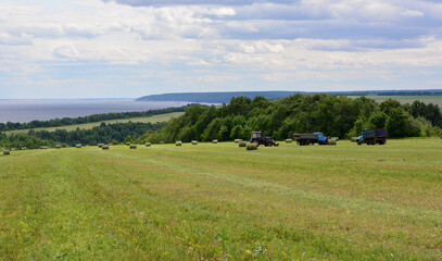 a field with a tractor and a blue truck and forest in the background copy space