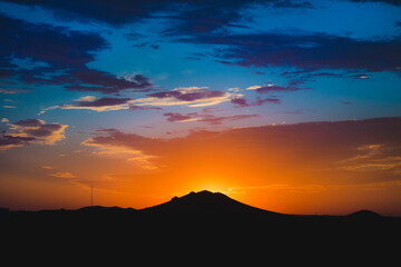 Bright vibrant colorful desert sunrise behind mountain silhouette