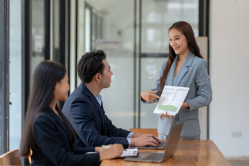 Fototapeta premium Business team discussion in an office setting with a woman presenting a chart to colleagues for a project meeting.