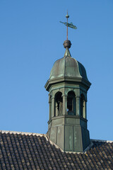 Spire on Nordby Church in copper against the black tile roof and a beautiful blue sky