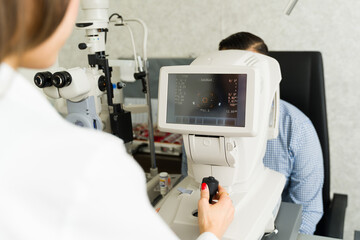 Ophthalmologist operates advanced diagnostic equipment during an eye exam with a patient in a...