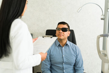 Ophthalmologist discusses eye health with a male patient wearing an eye patch during a routine check-up in a modern clinic
