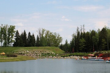 an amusement park pond with a pier surrounded by a forest and green environment