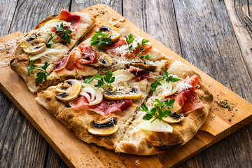 Roman Pizza with mozzarella cheese, cured ham and mushrooms on wooden table
