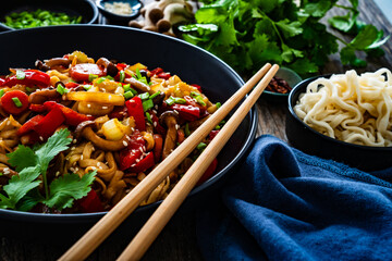 Asian style stir fried vegetables and noodles on wooden table
