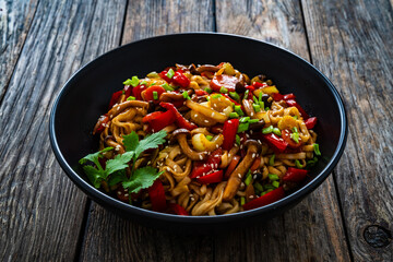 Asian style stir fried vegetables and noodles on wooden table
